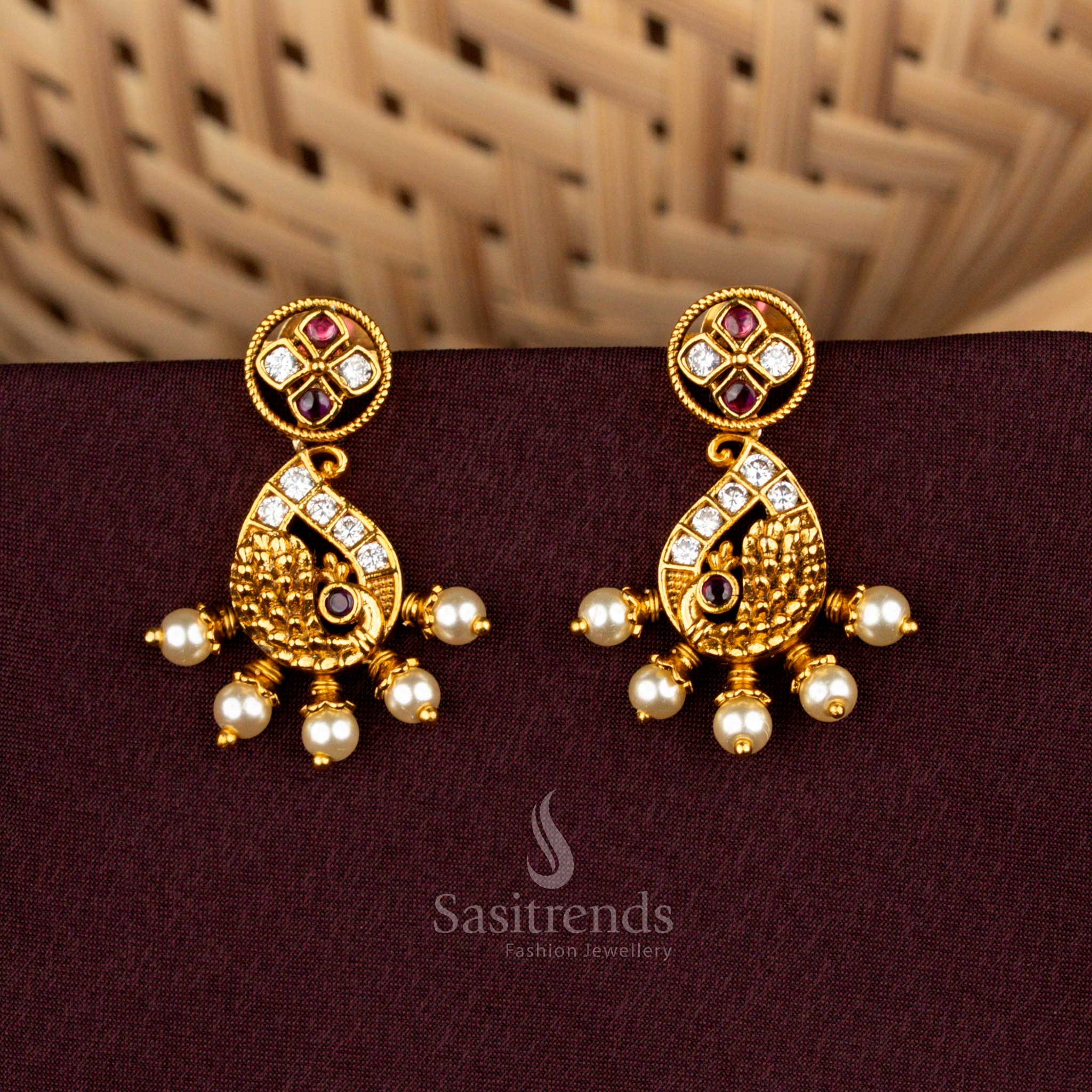 Splendid white ruby stud earrings featuring paisley peacock artistry, radiant matte gold detailing, aristocratic AD brilliance, and divine pearl drops for bridal grandeur – Sasitrends