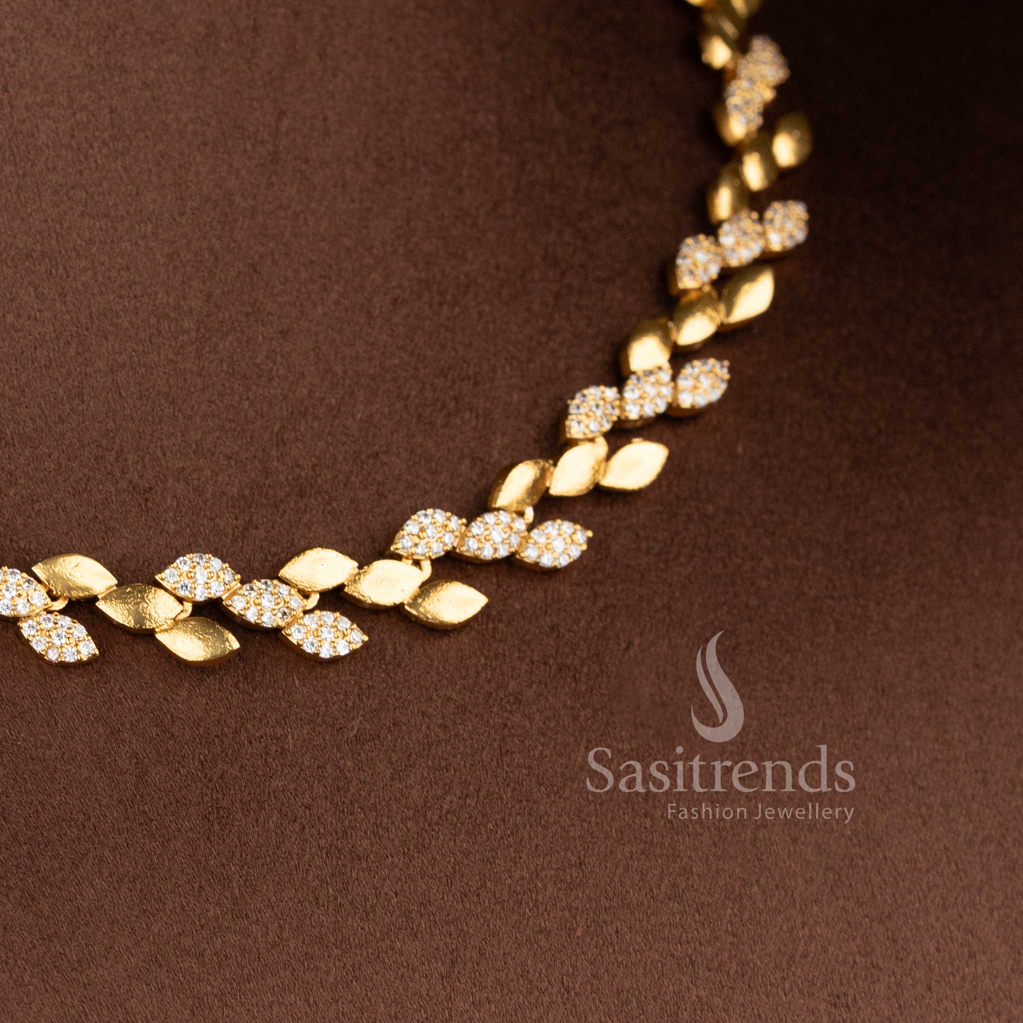 Close-up of the jewellery set showing the contrast between the smooth matte gold leaves and the shimmering stone-studded motifs - Sasitrends