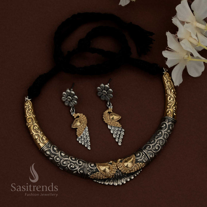 Sasitrends 92.5 dual tone silver oxidised husli jewellery set featuring a bold crescent necklace design with engraved scrollwork patterns, raised floral embossed elements, central peacock motif detailing, structured surface finish, traditional thread fastening, and matching earrings designed with floral studs and layered peacock-inspired drops for ethnic heritage wear.