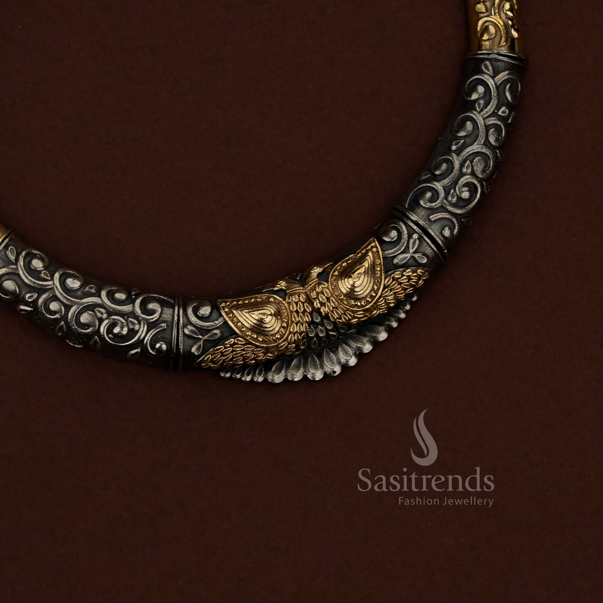 Sasitrends oxidised silver husli necklace jewellery set showcasing detailed floral embossing combined with sculpted peacock motif design, continuous engraved scrollwork across the curved structure, dual tone surface detailing, and coordinated earrings reflecting floral and peacock design elements suitable for festive and cultural occasions.