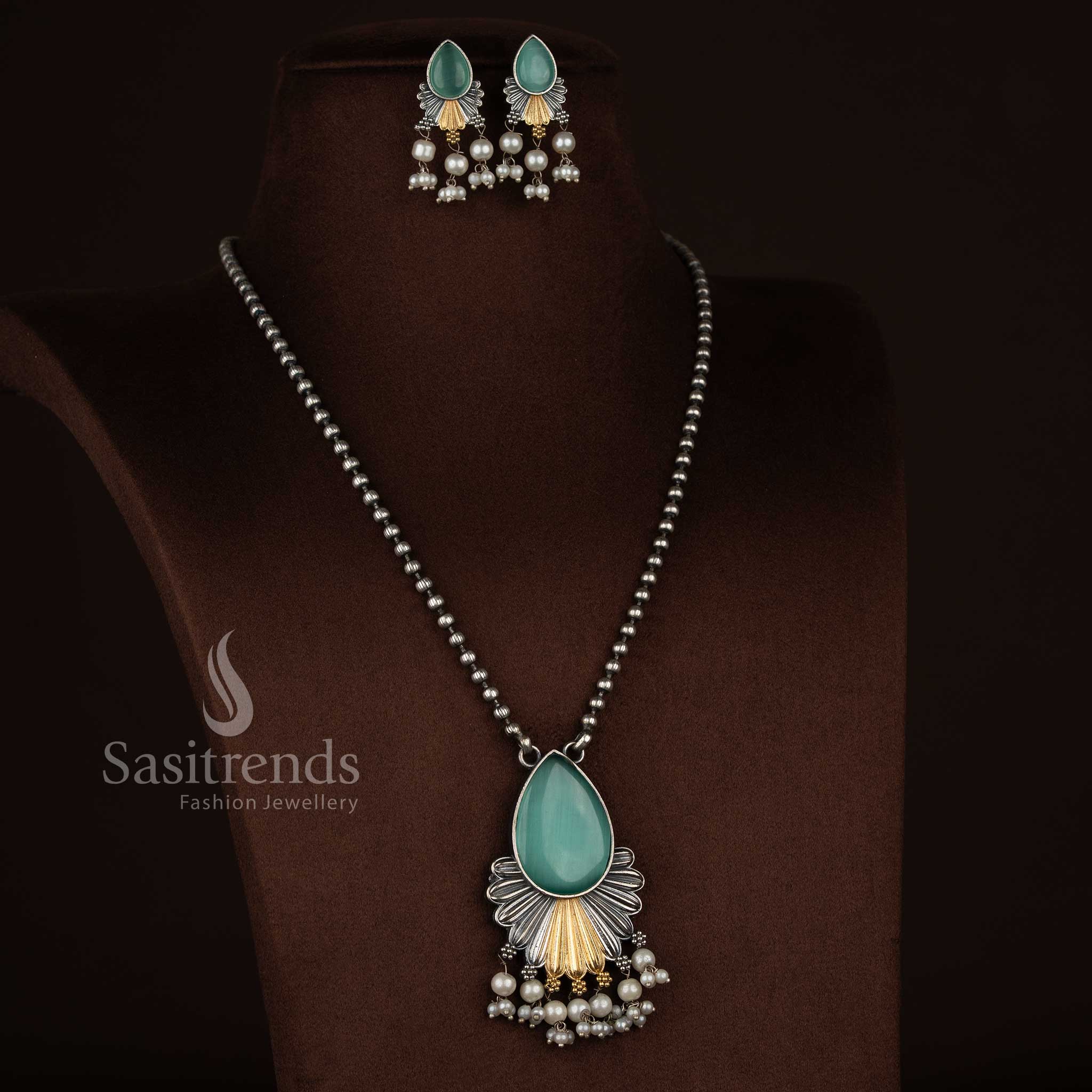 Antique oxidised 92.5 silver plated Monalisa stone jewellery set in mint shade, showcasing a floral inspired layered drop pendant, fan-textured silver framework, dual tone detailing, pearl hangings, oxidised beaded chain, and matching floral earrings with pearl accents - Sasitrends
