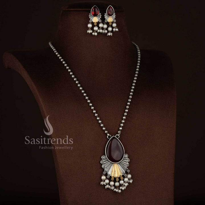 
Antique oxidised 92.5 silver plated Monalisa stone necklace jewellery set in red shade, featuring a teardrop floral layered drop pendant with fan-style silver structure, gold tone accents, pearl bead hangings, oxidised beaded chain, and matching floral earrings with pearl detailing
