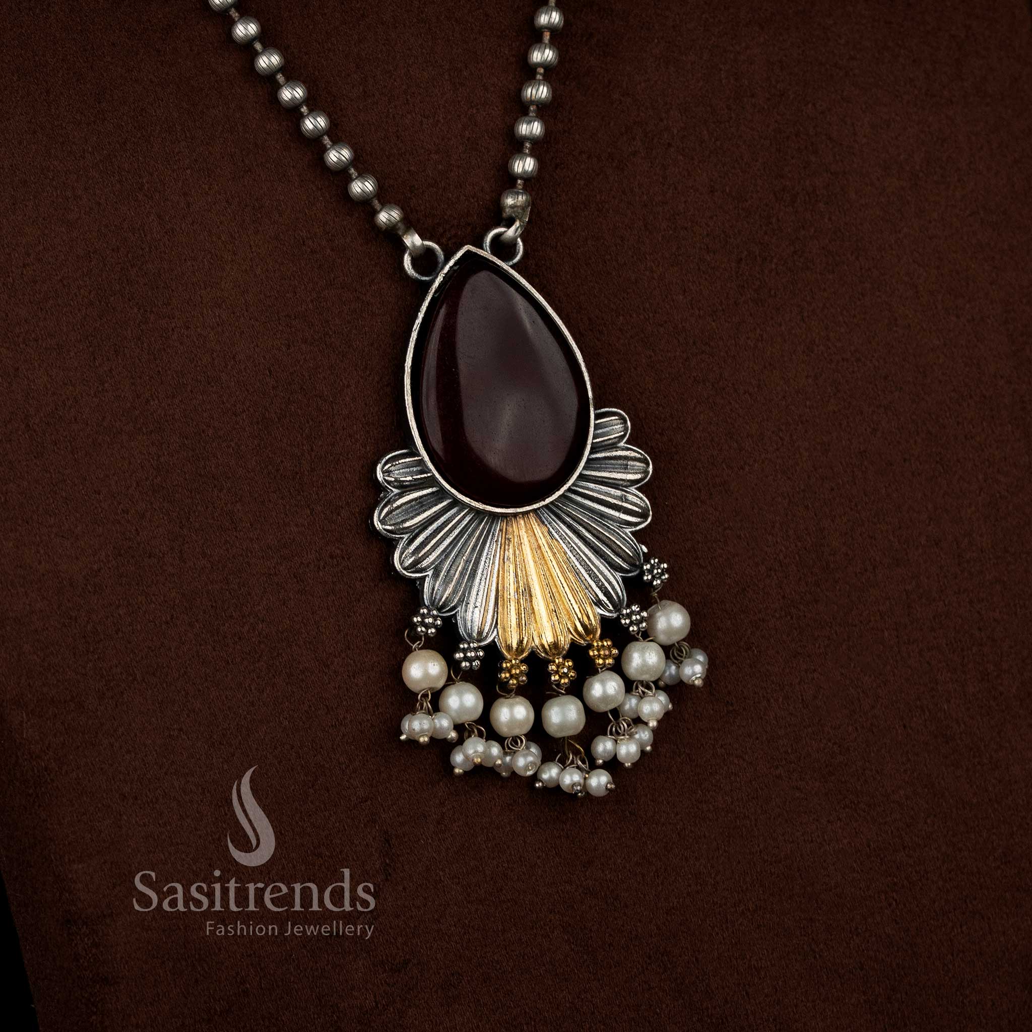 Antique oxidised 92.5 silver plated Monalisa stone necklace set in red shade, crafted with a floral inspired layered drop pendant, detailed silver textures, gold tone accents, pearl bead hangings, oxidised beaded chain, and matching floral drop earrings - Sasitrends
