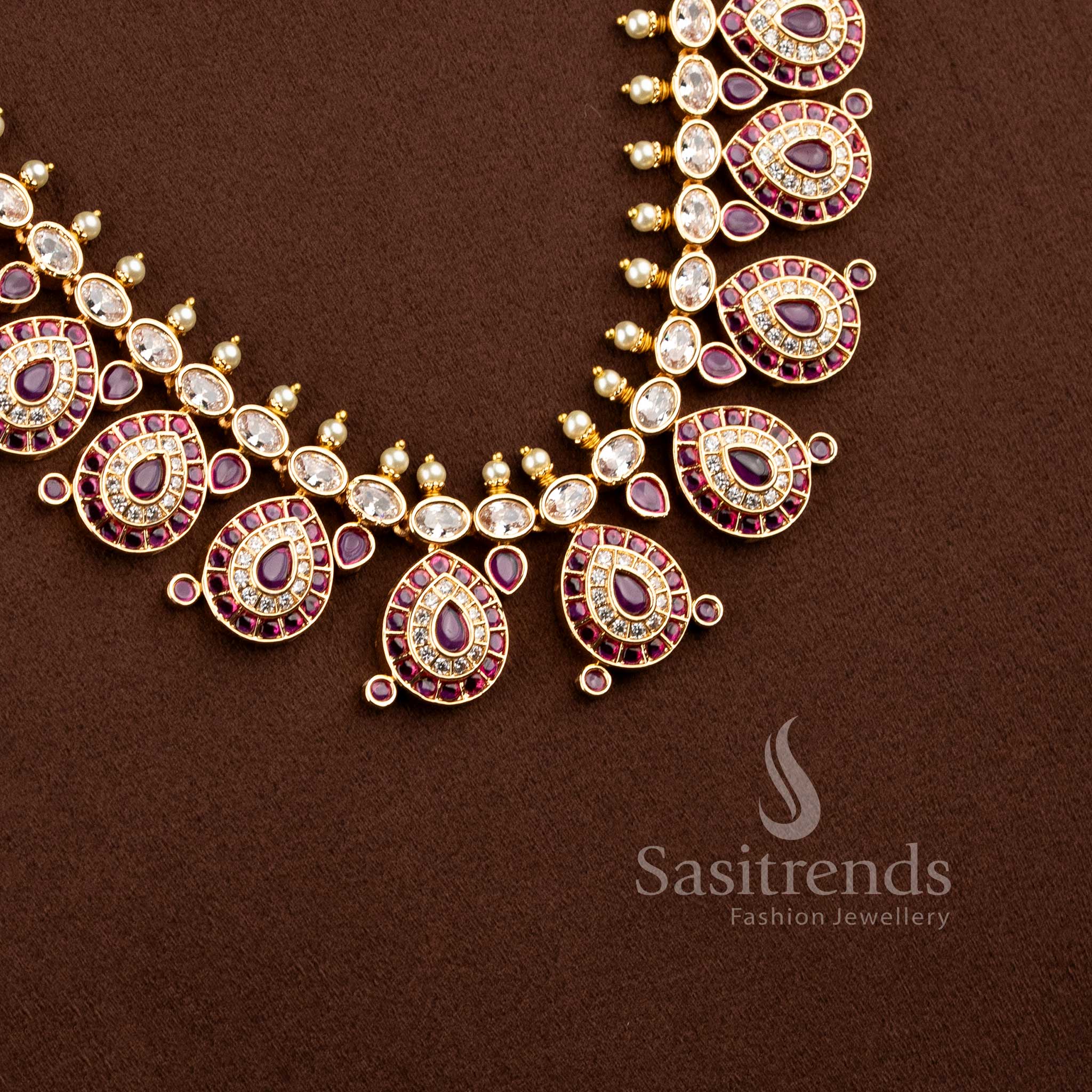 Close-up of an elegant wedding wear interlocking paisley leaf necklace layout with pink stones and pearl bead drops.