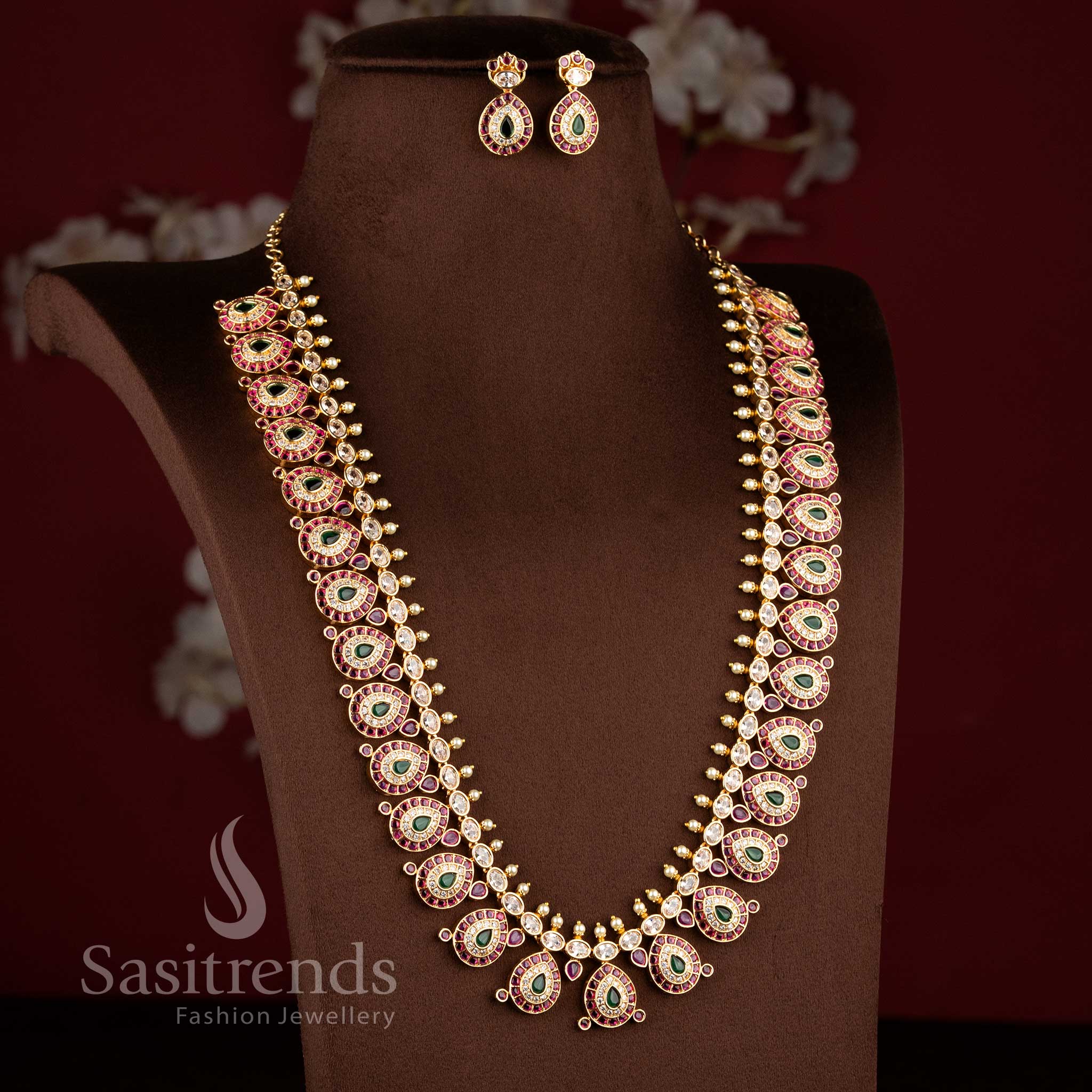 Close-up of an elegant wedding wear interlocking paisley leaf necklace layout with pink stones and pearl bead drops.