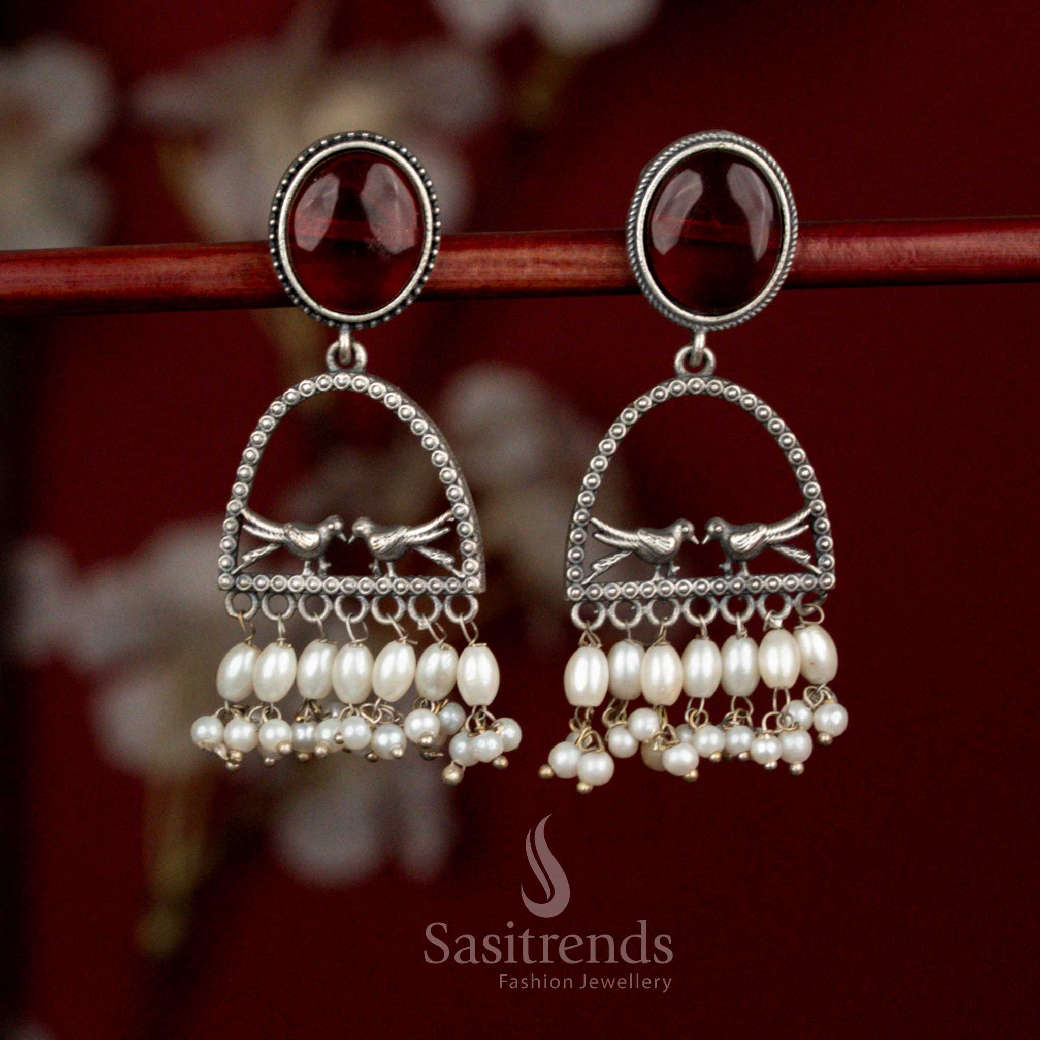 Deep toned oxidised 92.5 silver earrings featuring maroon Monalisa stone, curved dual bird arch design and pearl detailing for expressive ethnic looks - Sasitrends