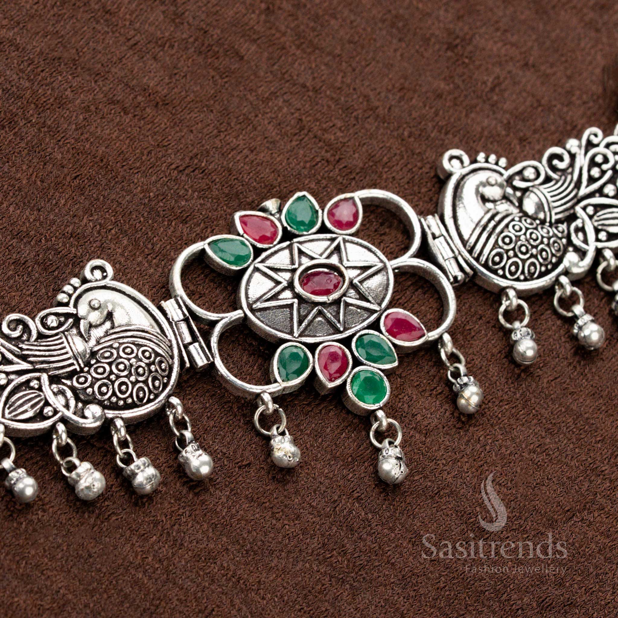 Traditional oxidised necklace set featuring ruby and green gemstones, dual peacock patterns, a central floral design, and teardrop elements, offering an exquisite bridal jewellery experience - Sasitrends