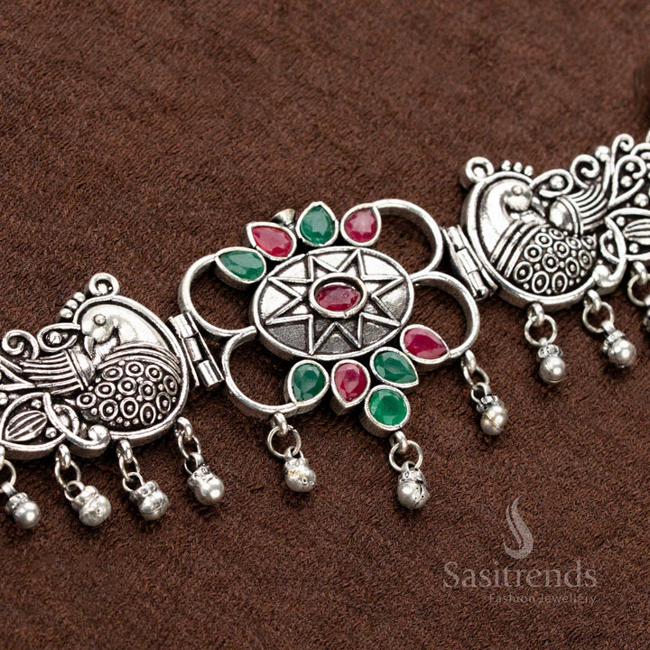 Traditional oxidised necklace set featuring ruby and green gemstones, dual peacock patterns, a central floral design, and teardrop elements, offering an exquisite bridal jewellery experience - Sasitrends