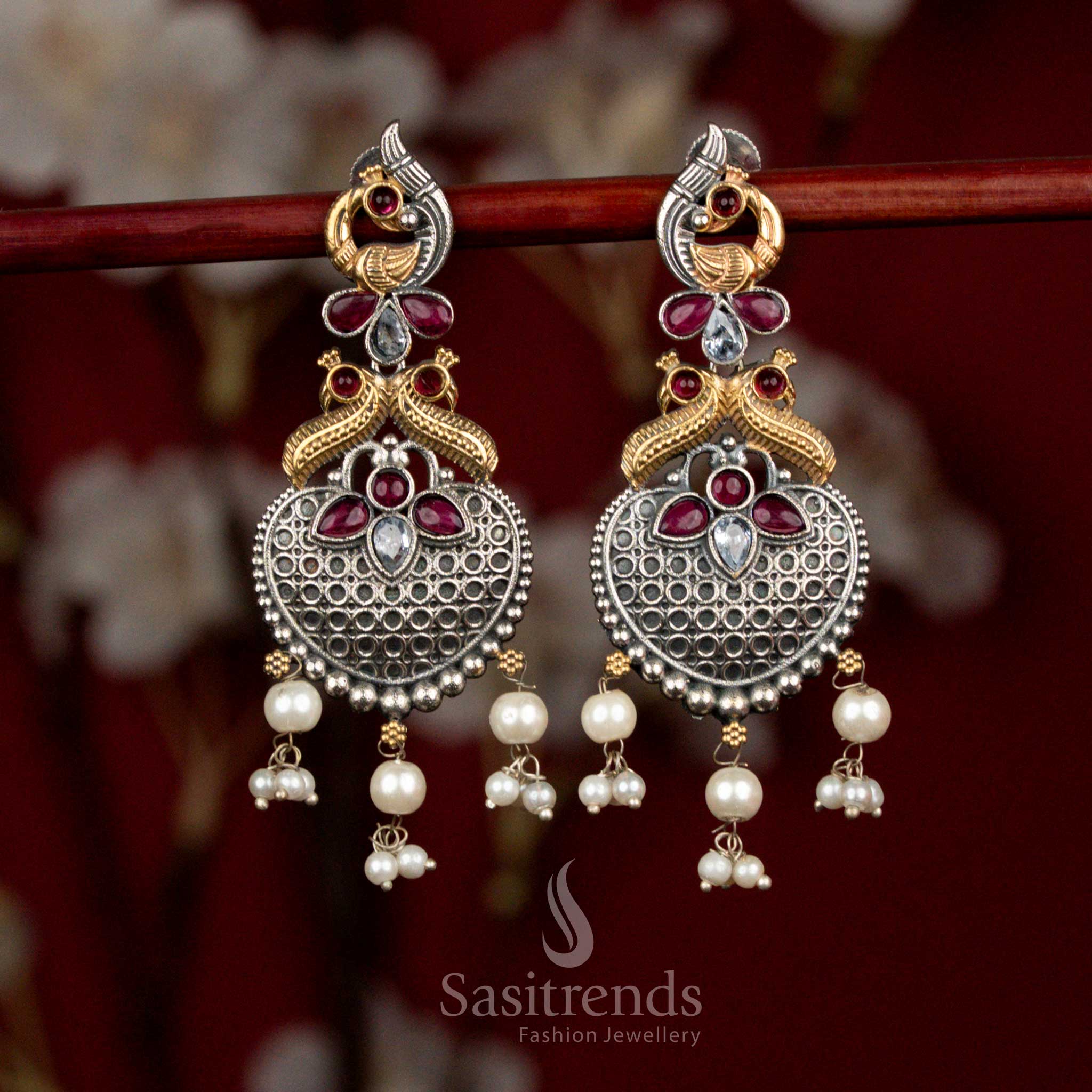 Bold dual tone oxidised silver earrings adorned with white ruby Monalisa stones, intricately sculpted peacock heart design and pearl cluster hangings for expressive ethnic wear - Sasitrends