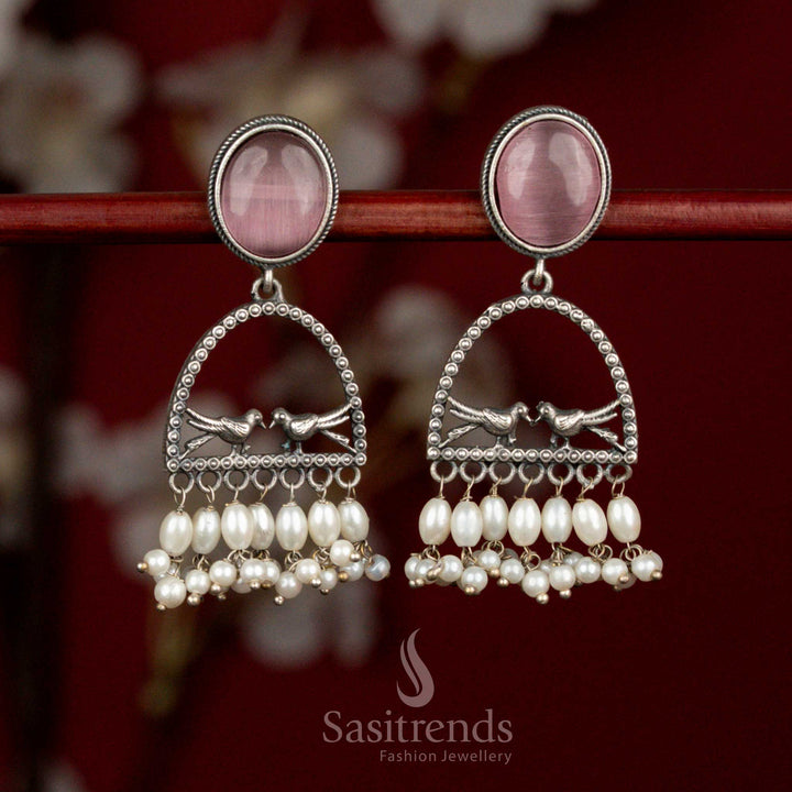 Elegant oxidised silver earrings featuring pink Monalisa stone, sculpted dual bird arch design, spherical elements and rice pearls for artistic ethnic wear - Sasitrends