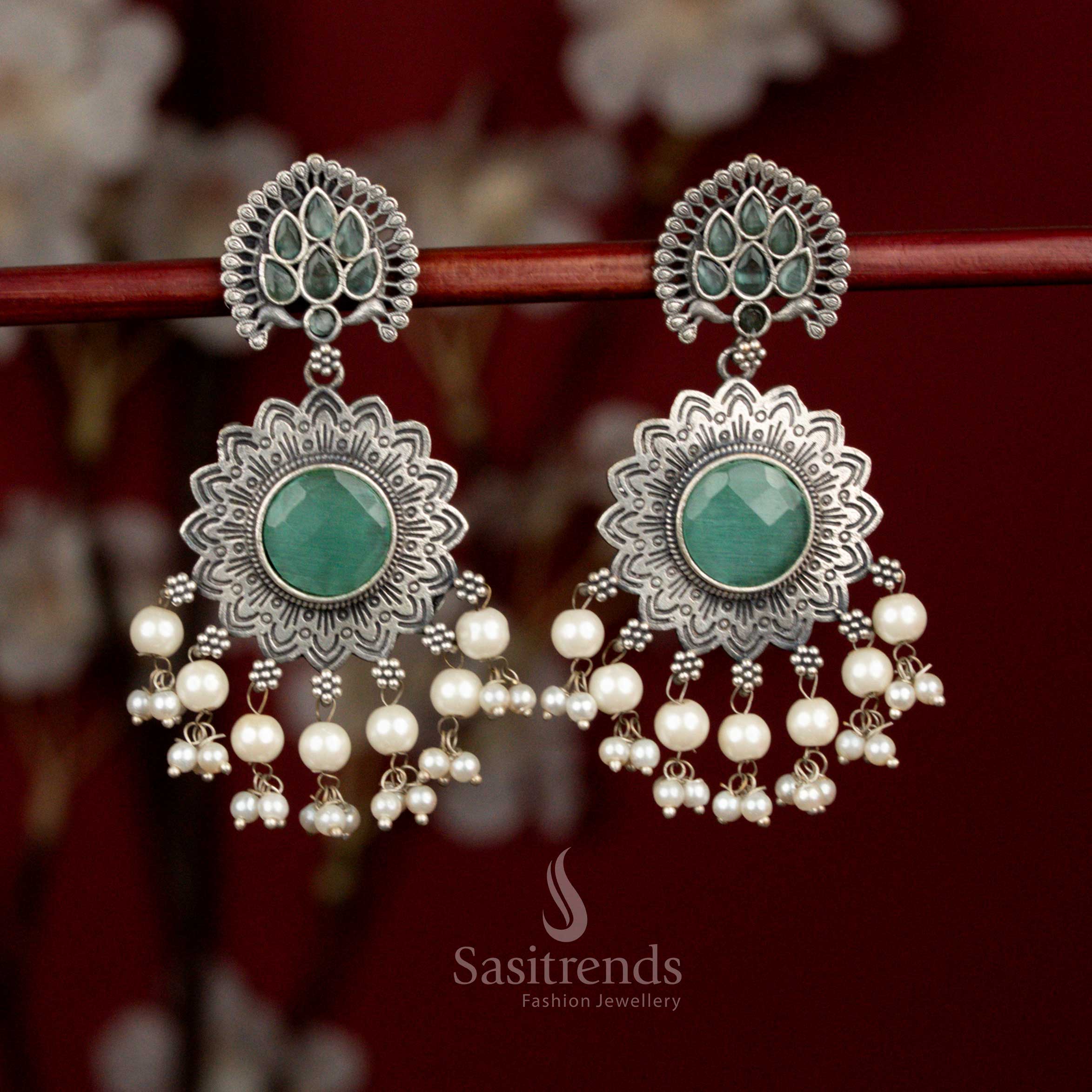 Antique oxidised silver plated earrings designed with mint Monalisa stones, sunburst peacock feather floral motif and pearl detailing for refined party looks - Sasitrends
