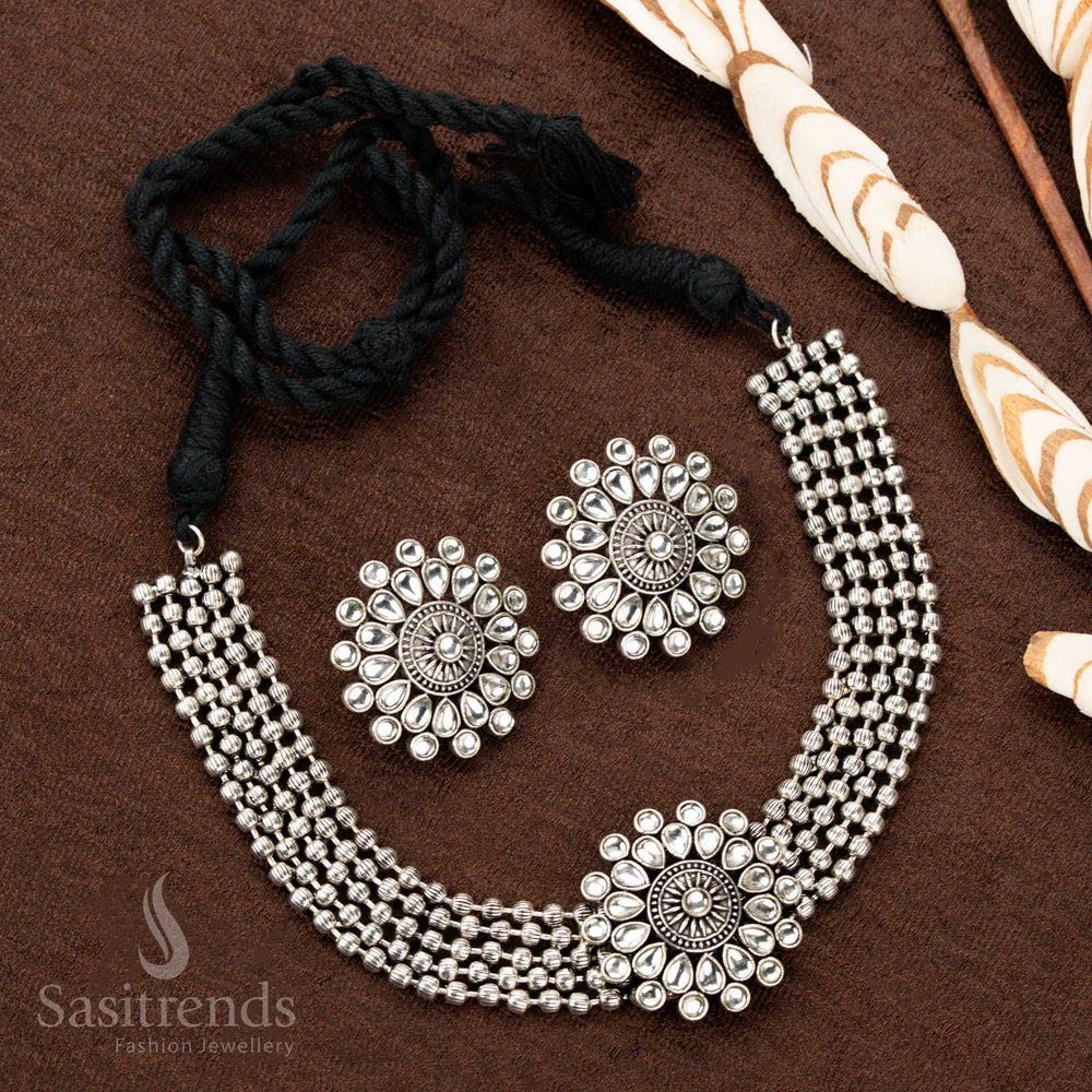 Majestic oxidised German silver choker necklace adorned with a floral pendant featuring sparkling white stones, paired with matching earrings, a refined choice for Navaratri and festive looks - Sasitrends