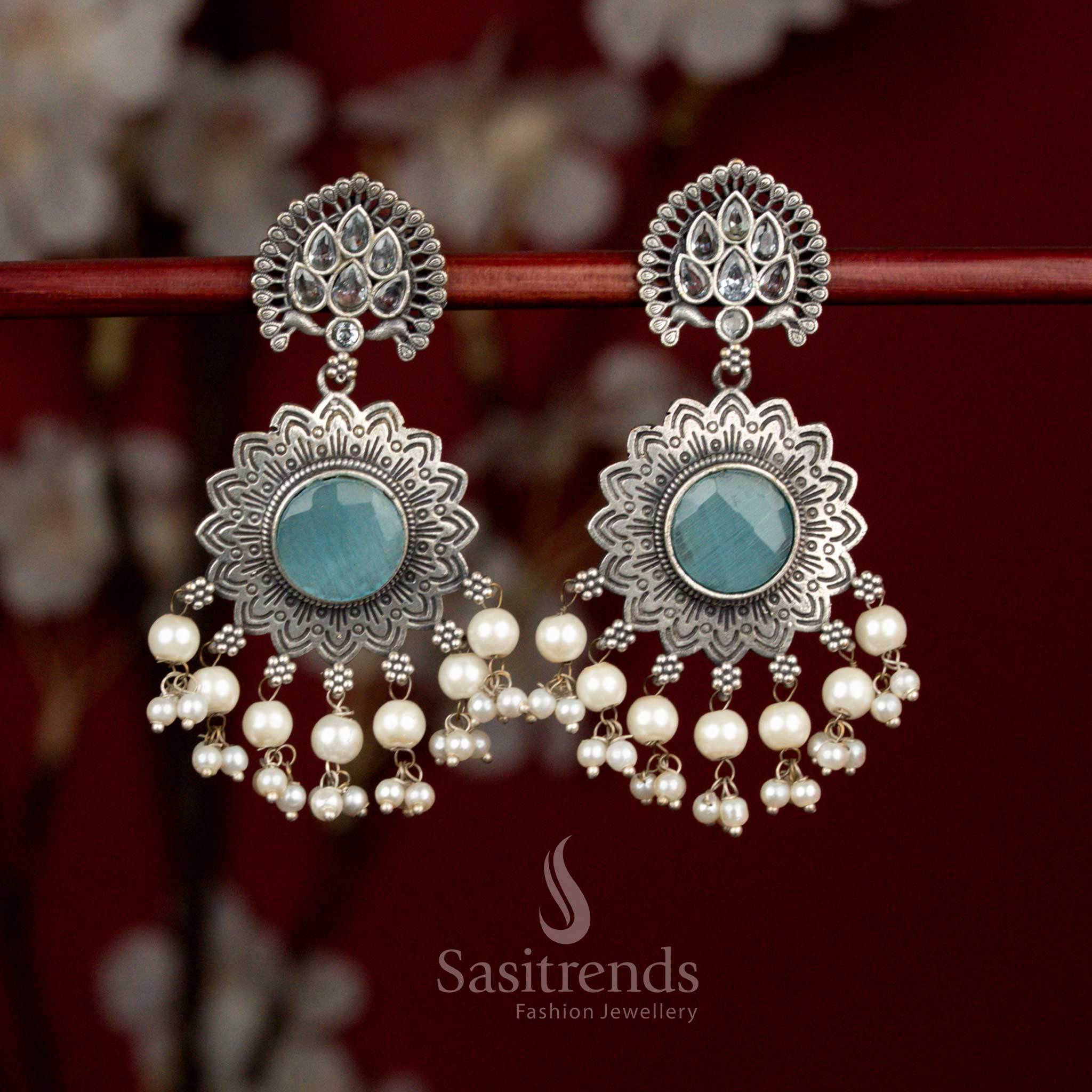 Antique oxidised silver earrings featuring sky blue white Monalisa stones, airy peacock feather sun motif and pearl details for graceful party styling - Sasitrends