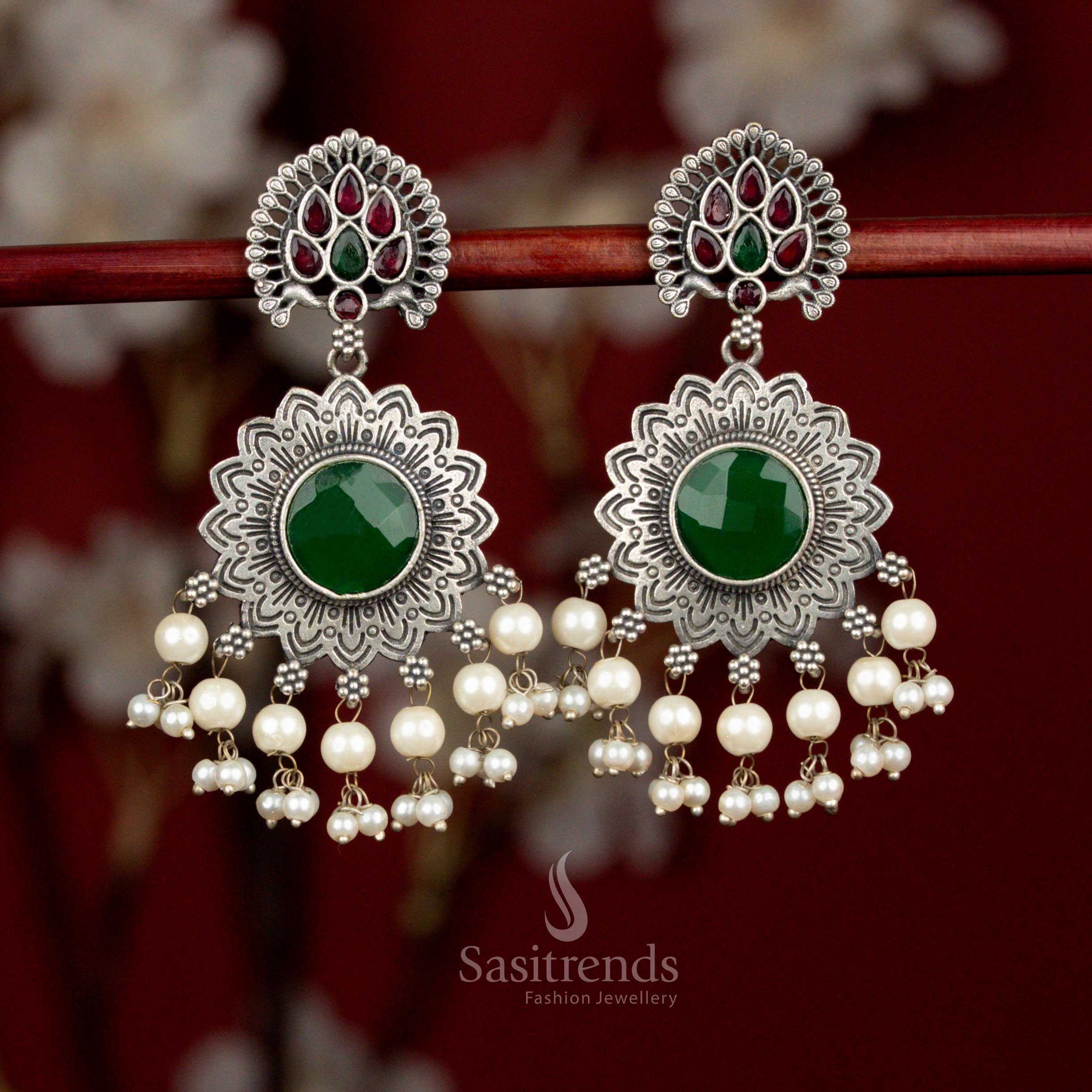 Antique oxidised silver earrings accented with ruby and green Monalisa stones, layered peacock sun floral motif and pearl elements for vibrant styling - Sasitrends