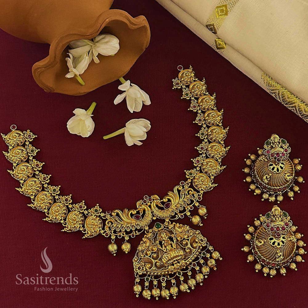 Trendy temple matte gold bridal jewellery set with ruby-green stones, Lakshmi peacock pendant, and filigree jhumkas, curated for traditional celebrations and ceremonial elegance – Sasitrends