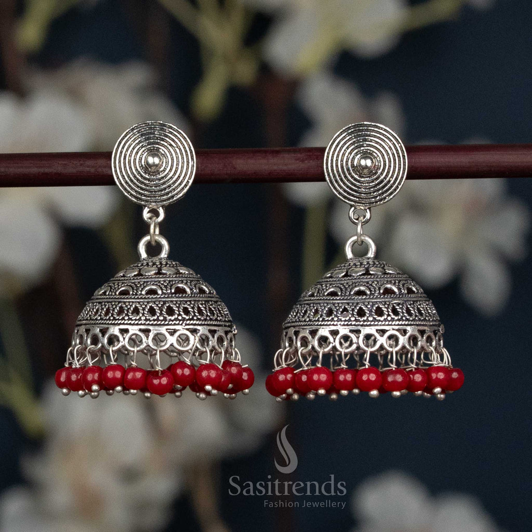 Oxidised German Silver Jhumka Earrings With Spiral Stud Design, Maroon Stone Centrepiece, And Dangling Red Bead Details For Grand Festive Looks – Sasitrends