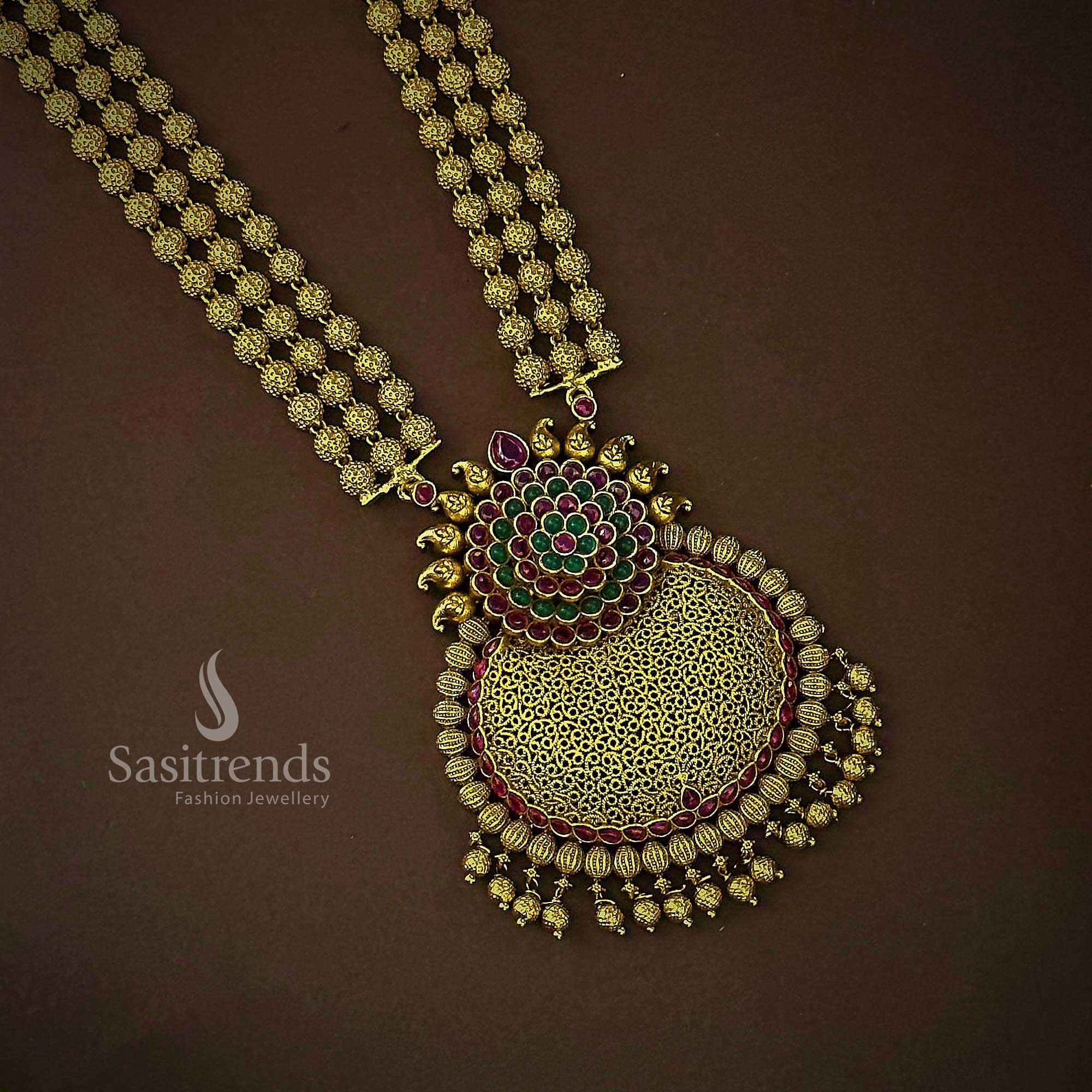 Grand traditional bridal temple jewellery set in matte gold featuring an elaborate three-layered bead floral pendant and handcrafted jhumkas, accented with rich ruby-green stones for timeless bridal splendor – Sasitrends
