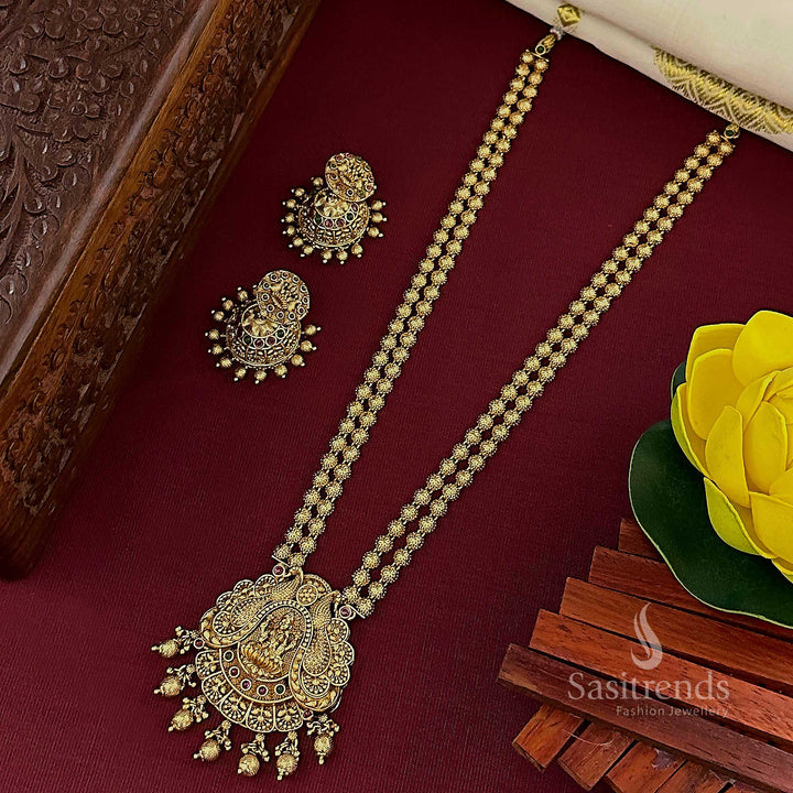 Traditional temple matte gold plated Lakshmi pendant 2-layer long jewellery set with exquisite jhumkas, featuring vibrant ruby-green stone accents for a majestic bridal look – Sasitrends

