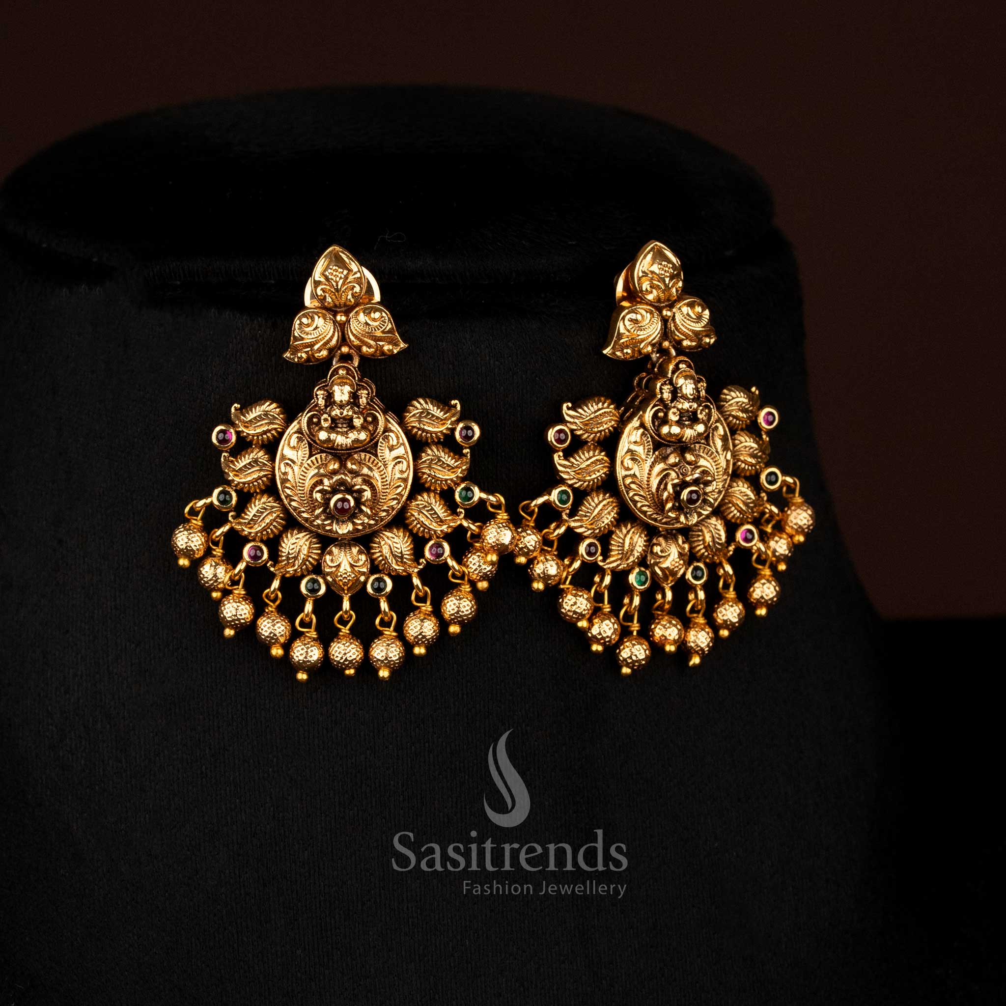 Gleaming ruby-green matte gold plated peacock Lakshmi earrings with floral accents and golden ball drops, designed to wear for vibrant festive occasions – Sasitrends
