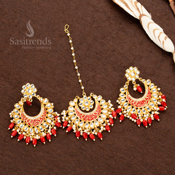 Traditional gold plated colourful painted earrings and tikka set adorned with rich red stone embellishments, intricate artistic detailing, and delicate bead drops - Sasitrends