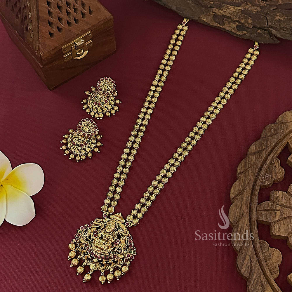 Temple matte gold finish bridal long jewellery set with detailed Lakshmi pendant and jhumkas in ruby-green stones, showcasing cultural elegance and festive grandeur – Sasitrends

