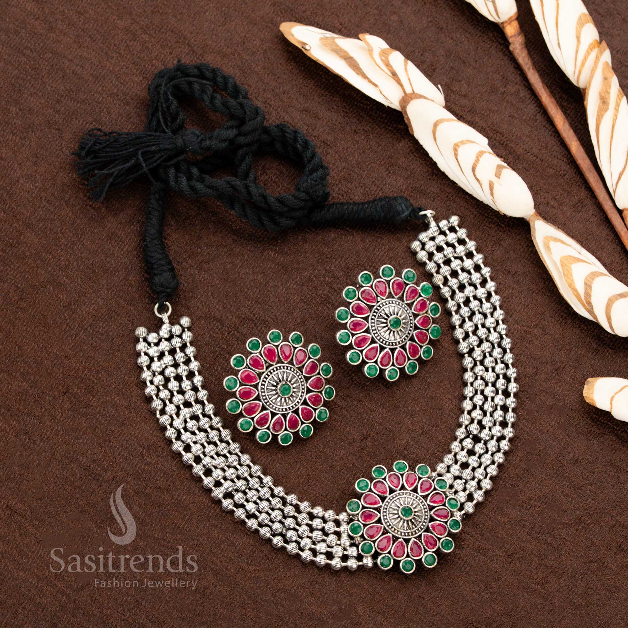 Antique oxidised German silver choker set featuring an intricately designed floral pendant with ruby and green gemstones, making it a stunning jewellery piece for ethnic fashion and festive celebrations - Sasitrends
