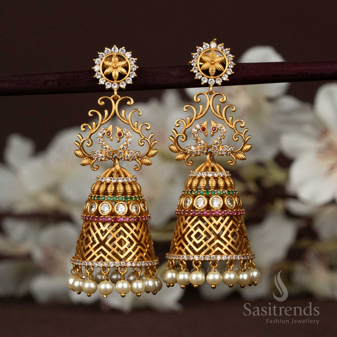 Radiant Jhumka earrings in matte gold, featuring peacock and floral motifs, accented with sparkling AD stones and soft pearl hangings – perfect for festive occasions – Sasitrends