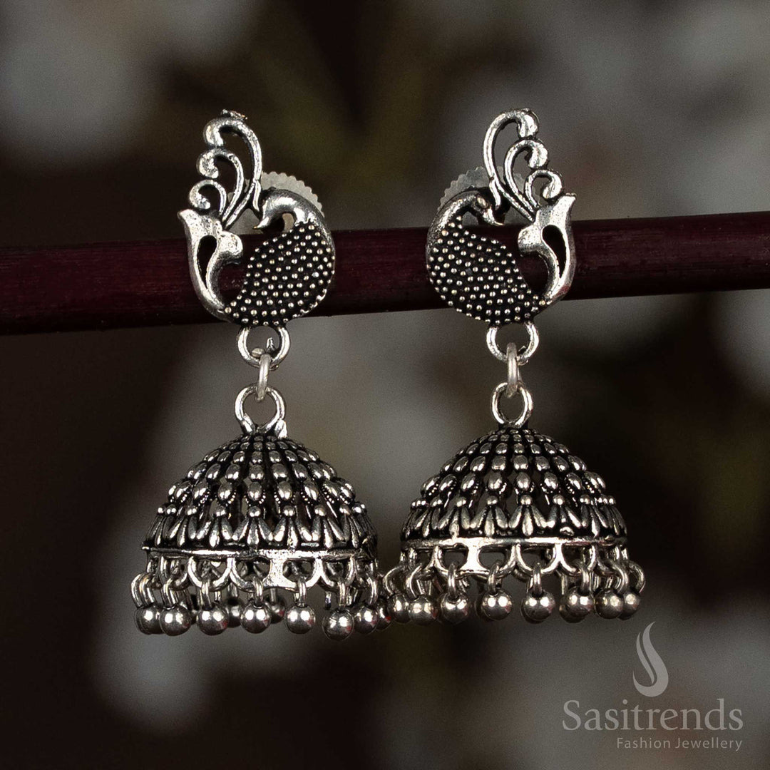 Antique-style oxidised silver jhumka earrings featuring a detailed peacock motif stud and floral-engraved dome, perfect for ethnic ensembles and cultural occasions – Sasitrends