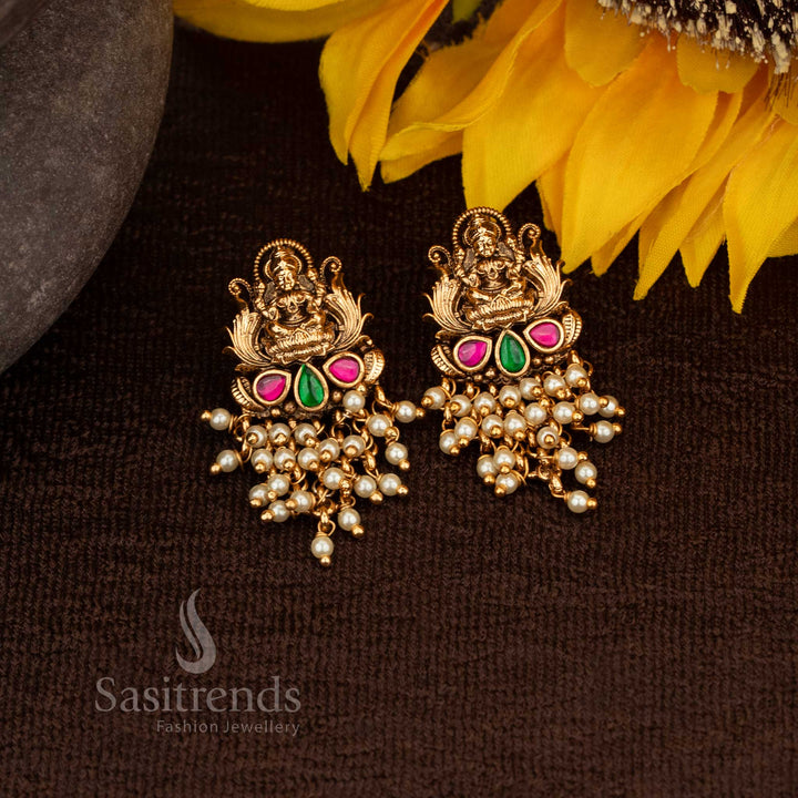 Exquisite matte gold Lakshmi temple earrings featuring ruby-green stones and refined pearl hangings, made for auspicious celebrations – Sasitrends