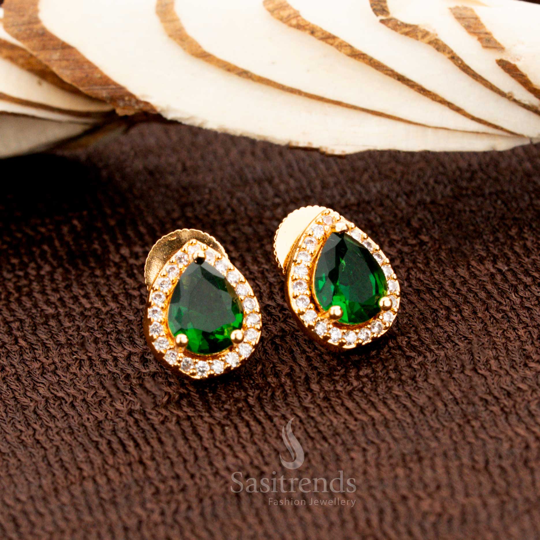 Exquisite gold-plated American diamond oval stud earrings with vibrant green stones, a perfect jewellery choice for weddings, festive wear, and regal ethnic fashion - Sasitrends