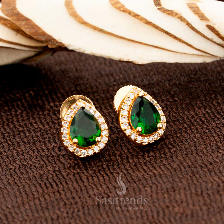 Exquisite gold-plated American diamond oval stud earrings with vibrant green stones, a perfect jewellery choice for weddings, festive wear, and regal ethnic fashion - Sasitrends