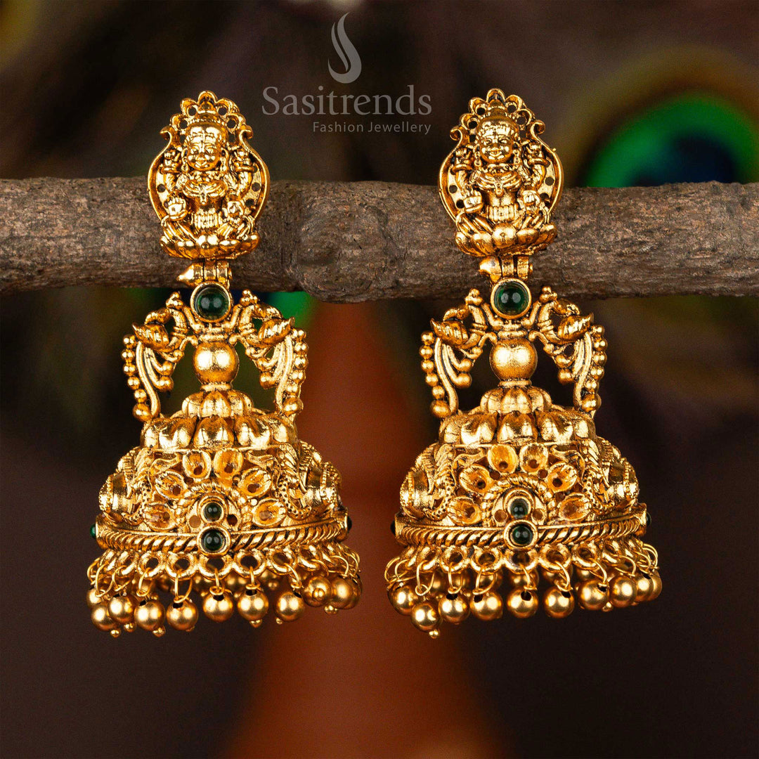 Matte gold plated temple-style green jhumka earrings with intricate Lakshmi deity and twin peacock pairings, finished with sculpted bead hangings – an emblem of forest grace and devotion – Sasitrends
