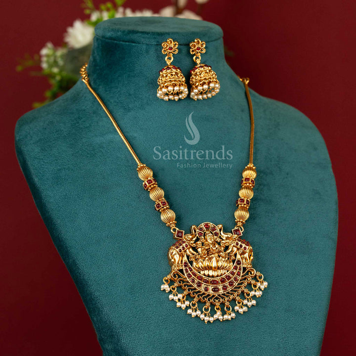 Elegant matte gold temple necklace featuring a radiant ruby stone Lakshmi pendant with matching floral jhumka earrings – designed for timeless bridal grace – Sasitrends