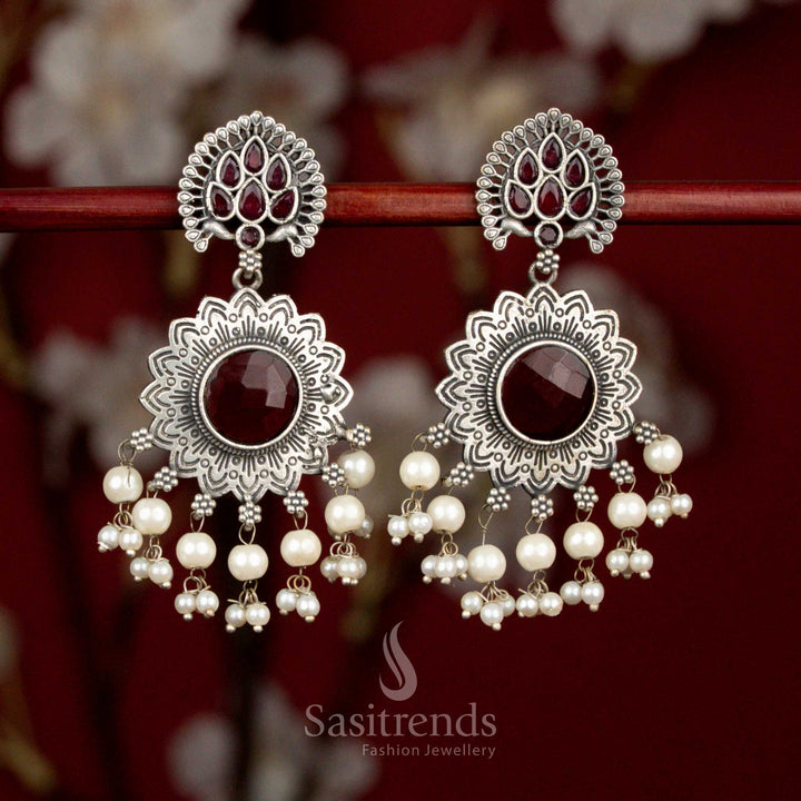 Antique 92.5 oxidised silver earrings showcasing ruby Monalisa teardrop stones, bold peacock sun floral structure and pearl highlights for striking party wear - Sasitrends