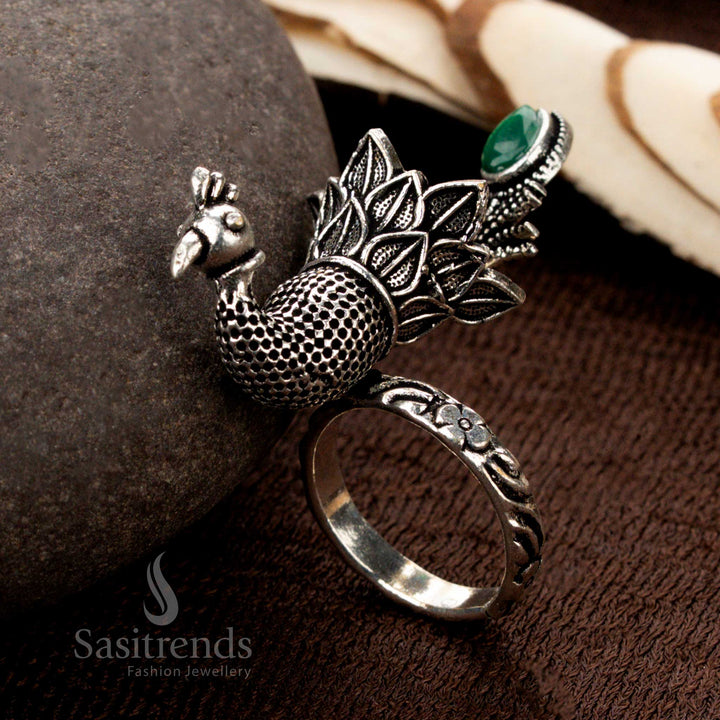 A heritage oxidised silver peacock design ring with handcrafted plume patterns, highlighting a lush green stone, perfect for adding a touch of elegance to ethnic jewellery - Sasitrends