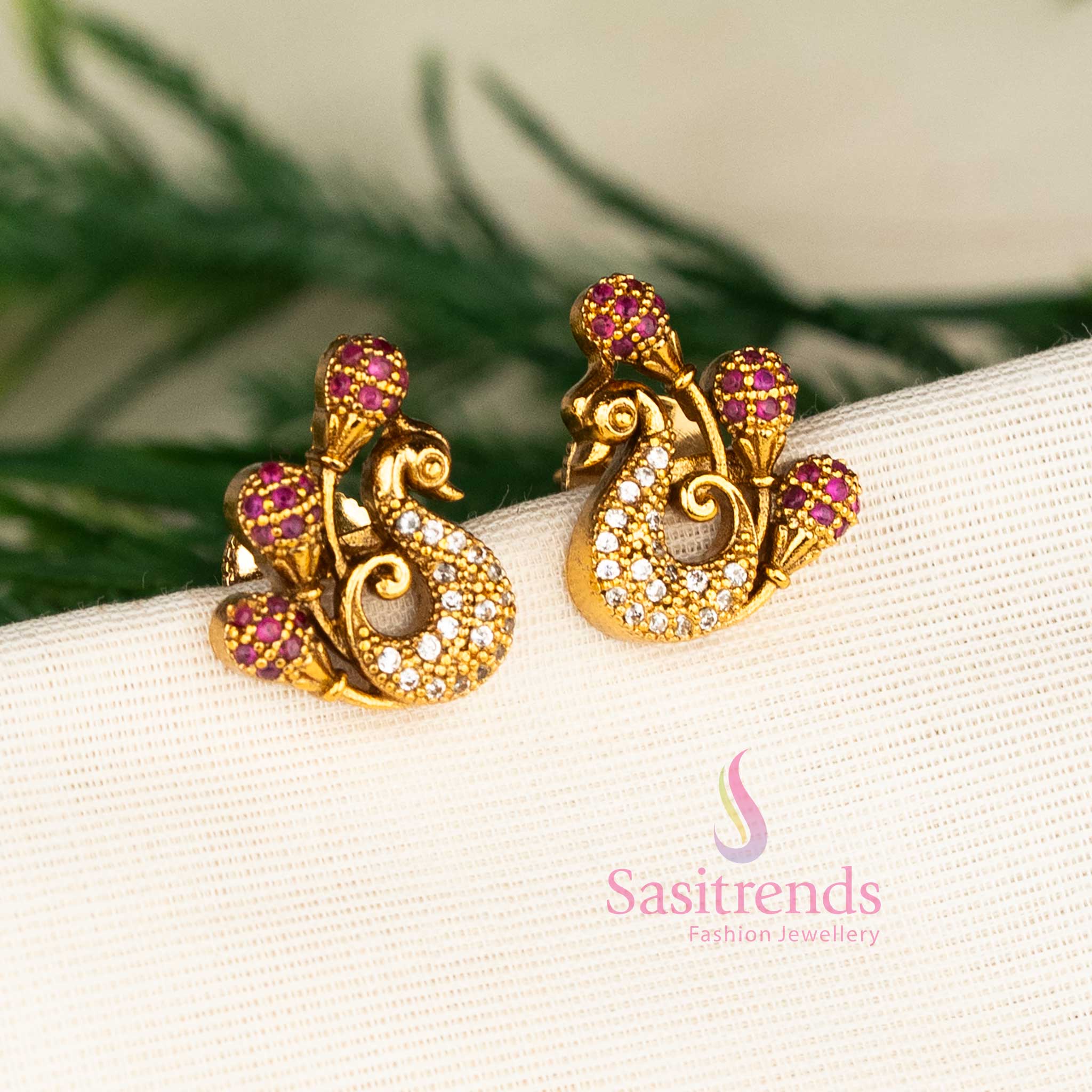 Premium matte gold ruby-white peacock stud earrings with two-tone American diamonds, designed for graceful traditional elegance and festive celebrations by Sasitrends.