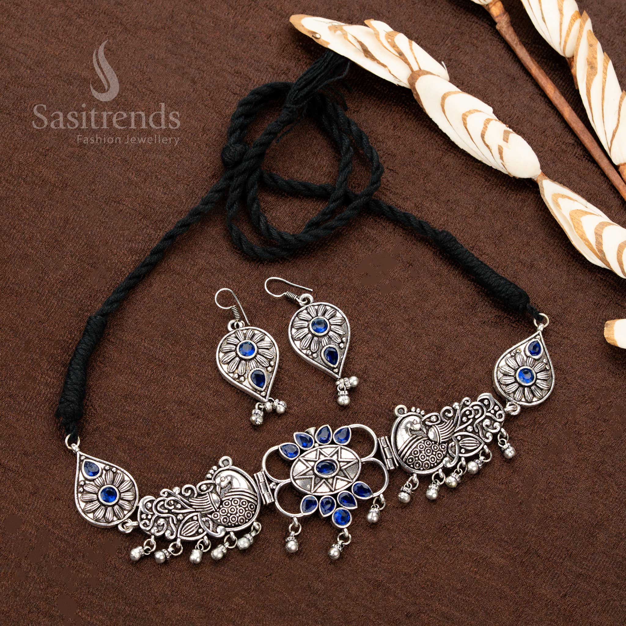 Majestic oxidised silver necklace set, adorned with cobalt blue stone details, intricate peacock motifs, floral patterns, and teardrop dangles, crafted for luxurious bridal jewellery collections - Sasitrends