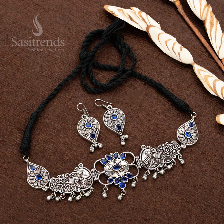 Majestic oxidised silver necklace set, adorned with cobalt blue stone details, intricate peacock motifs, floral patterns, and teardrop dangles, crafted for luxurious bridal jewellery collections - Sasitrends