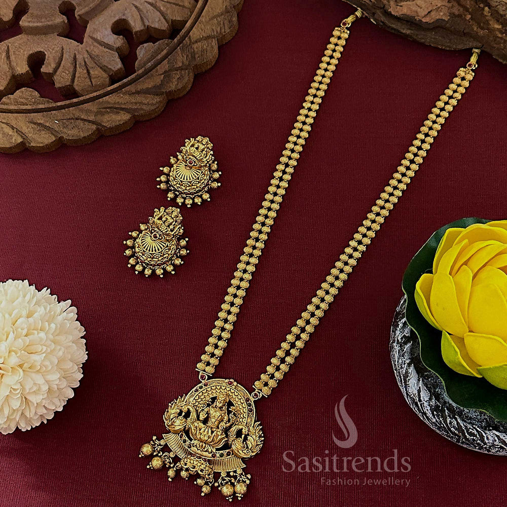 Bridal matte gold Lakshmi peacock pendant twin-layer long bead haram with ruby and emerald stone accents, finished with traditional jhumkas – a wedding jewellery masterpiece in South Indian style – sasitrends