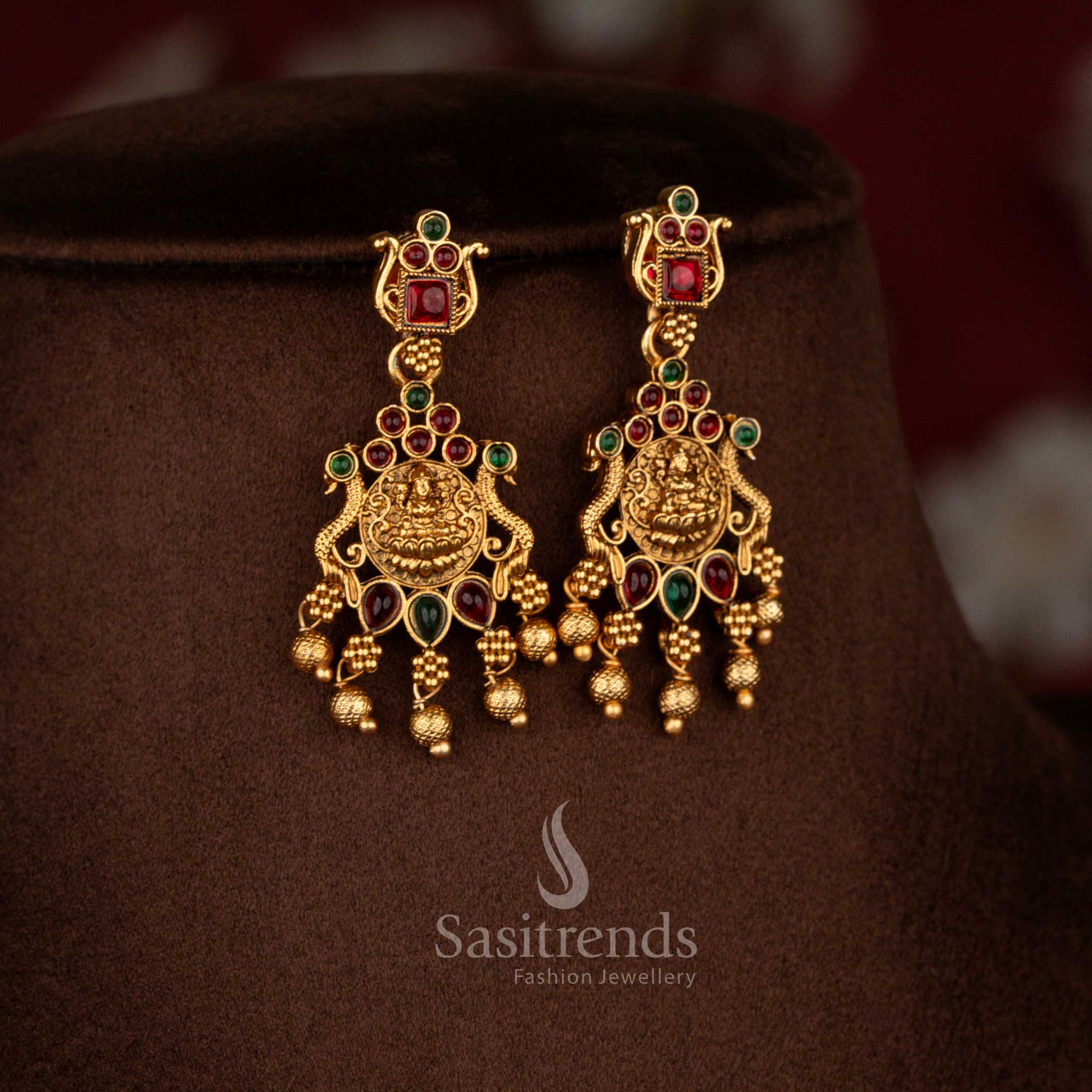 Radiant matte gold plated kemp peacock Lakshmi earrings with ghungroo drops in ruby green combination perfect for temple weddings and festive ceremonies – Sasitrends
