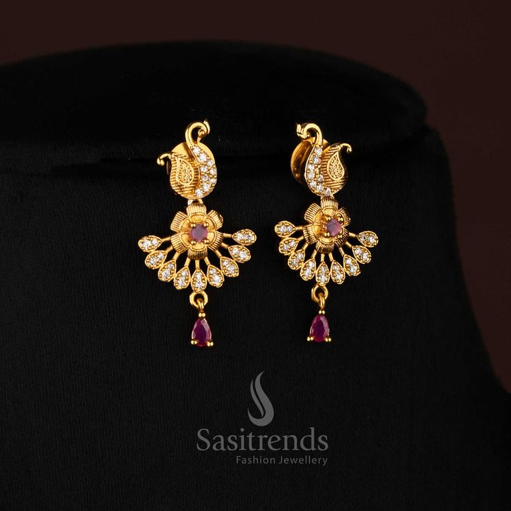 Royal matte gold peacock motif earrings embellished with sparkling white and ruby stones, paired with graceful floral accents for an opulent traditional jewellery finish ideal for weddings and festive celebrations – Sasitrends
