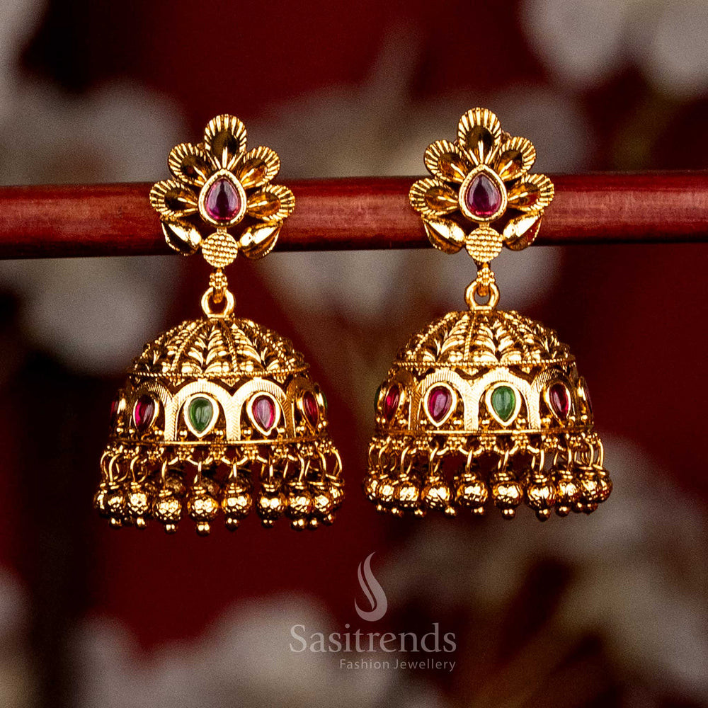 Grand temple inspired matte gold jhumka earrings featuring ruby-green accents, intricate floral petal layers, graceful teardrop dome form and traditional gold bead drops for statement festive styling - Sasitrends