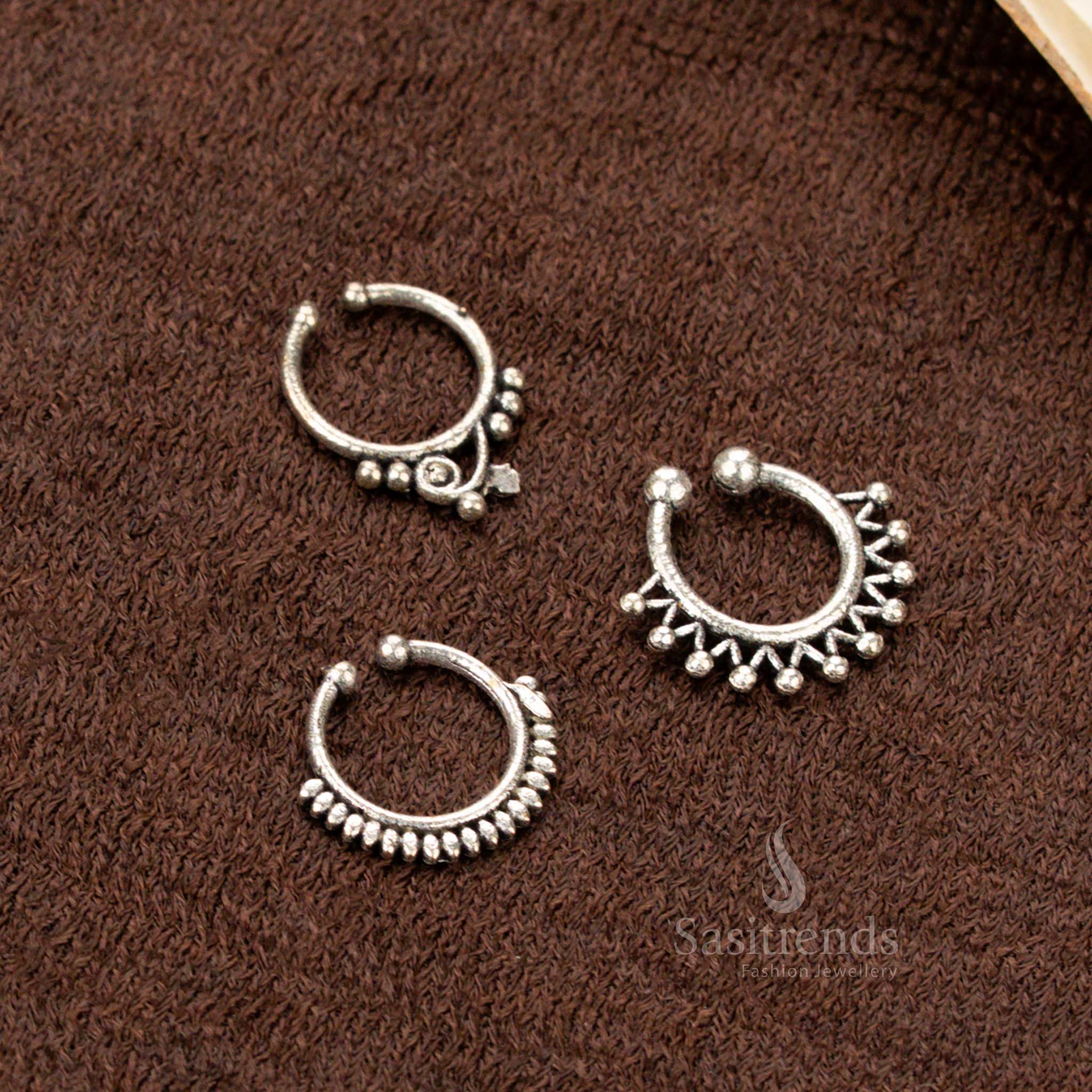 Vintage-inspired oxidised pressable nosepin set with tribal star, lotus, and bell motifs, crafted in silver-look finish with ethnic glam and handcrafted finesse by Sasitrends