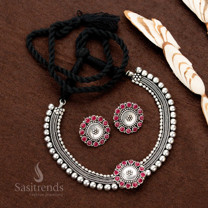 Deep crimson-toned Kolapuri choker set in oxidised dual-tone metal, adorned with ruby stone floral patterns, perfect for festive sarees and celebratory ethnic wear - Sasitrends
