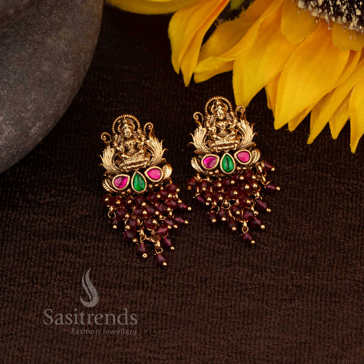 Premium matte gold Lakshmi temple earrings adorned with dazzling ruby-green stones and luxurious pink pearl drops – an exquisite traditional festive jewellery masterpiece from Sasitrends