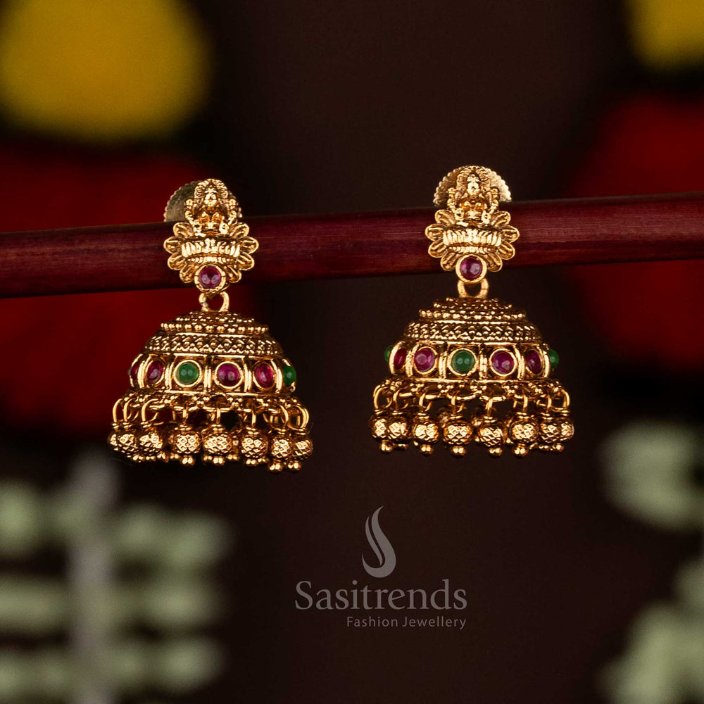 Magnificent ruby-green temple matte gold plated Lakshmi motif floral jhumka earrings with ghungroo drops, ideal for festive saree ensembles and ethnic charm by Sasitrends
