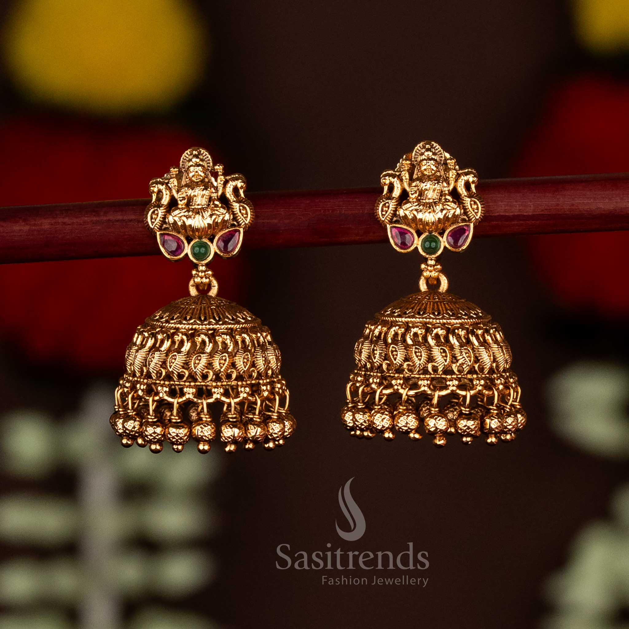 Stunning ruby-green matte gold plated Goddess Lakshmi jhumka earrings with beautiful cluster beads, designed for traditional bridal wear and grand cultural festivities by Sasitrends