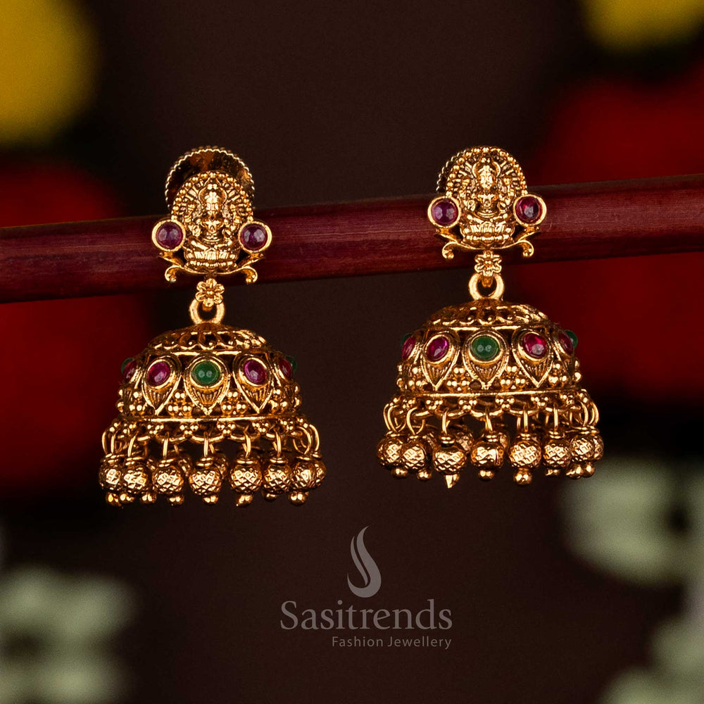 Majestic ruby-green temple matte gold plated Lakshmi motif jhumka earrings with ghungroo drops, crafted for ethnic festive elegance and grand celebrations by Sasitrends