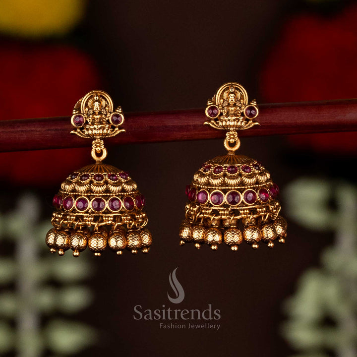 Radiant ruby divine temple matte gold plated Lakshmi heritage jhumka earrings with ghungroo drops, perfect for traditional festive wear and timeless cultural elegance by Sasitrends