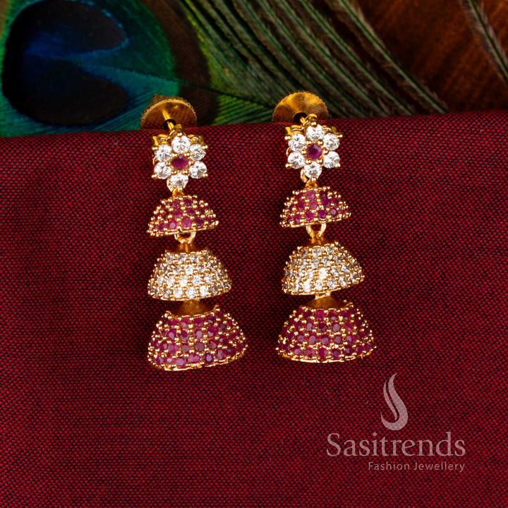 Exquisite Gold Plated Brass Triple-Layer Jhumkas with American Diamond Embellishments in White-Ruby Colour, Ideal Jewellery for Parties and Traditional Functions – Sasitrends